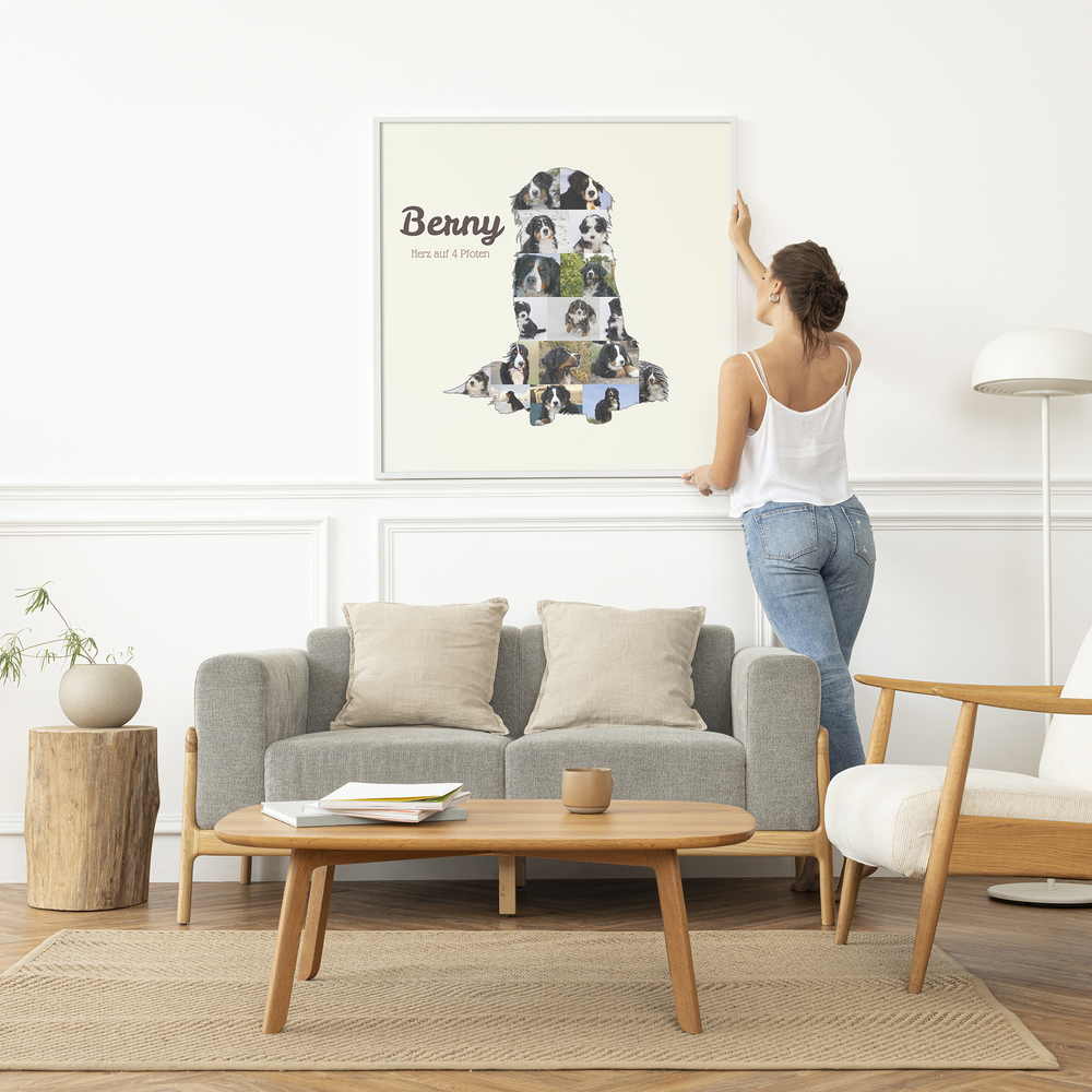 Fotocollage als sitzender Berner Sennenhund mit Namen im weißen Rahmen über einem grauen Sofa im hellen Wohnzimmer