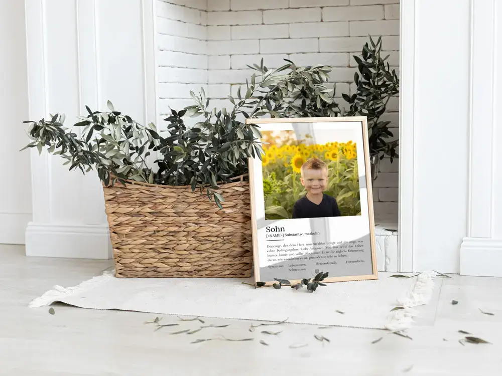 Definitionsposter für den Sohn mit großem Kinderfoto im hellen Rahmen, am Boden neben einem Pflanzenkorb