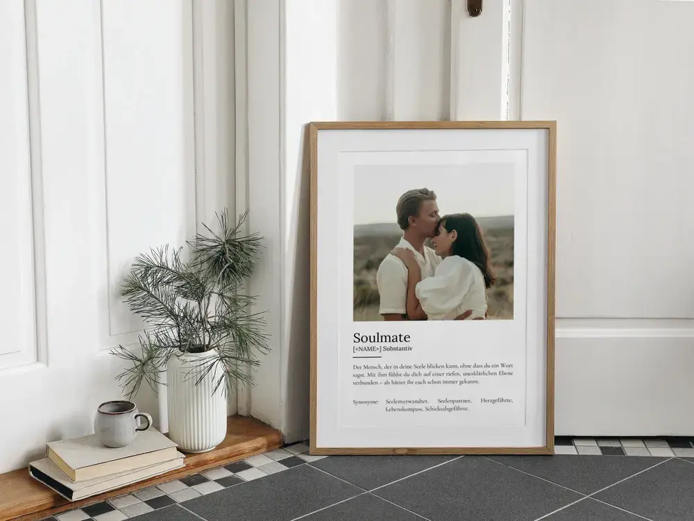 Definitionsposter mit Paarfoto und persönlichem Text im Holzrahmen, am Boden neben einer Pflanze