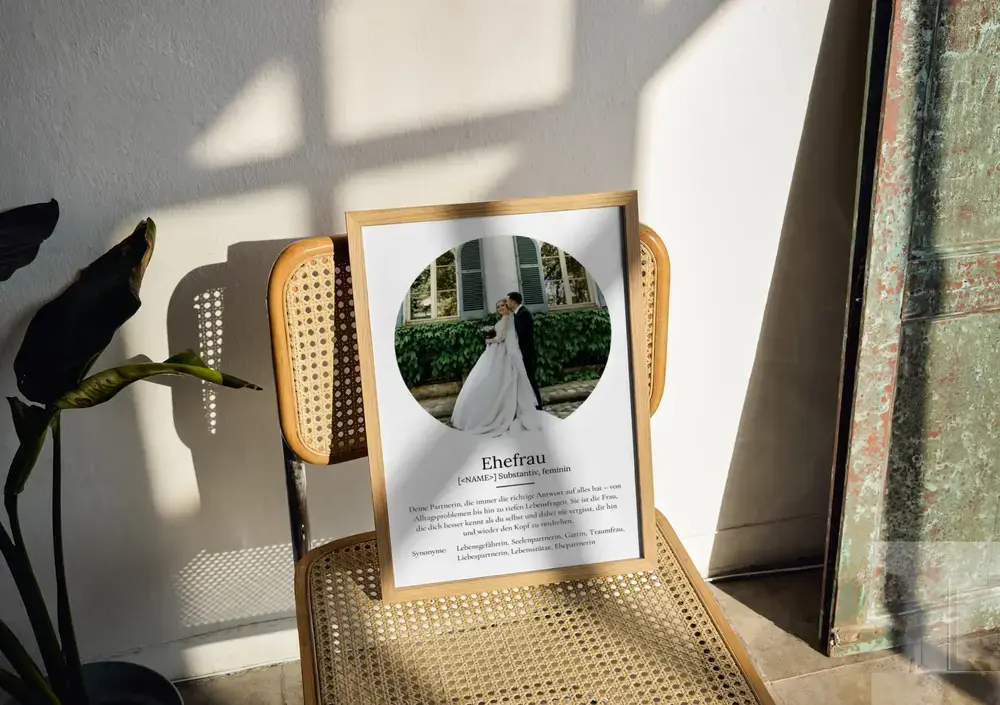 Definitionsposter mit rundem Hochzeitsfoto im Holzrahmen auf einem Geflechtstuhl, als Geschenk zum Hochzeitstag