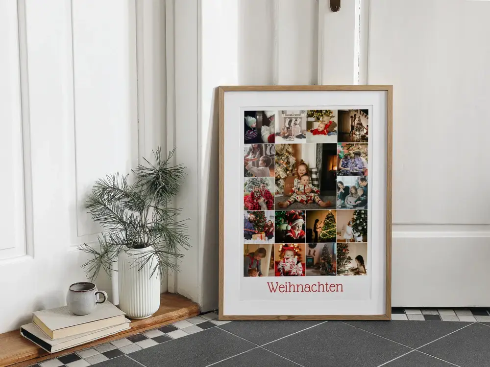 Weihnachts-Fotocollage mit rotem Schriftzug im Holzrahmen, am Boden vor weißer Wand neben einer Vase mit Zweigen