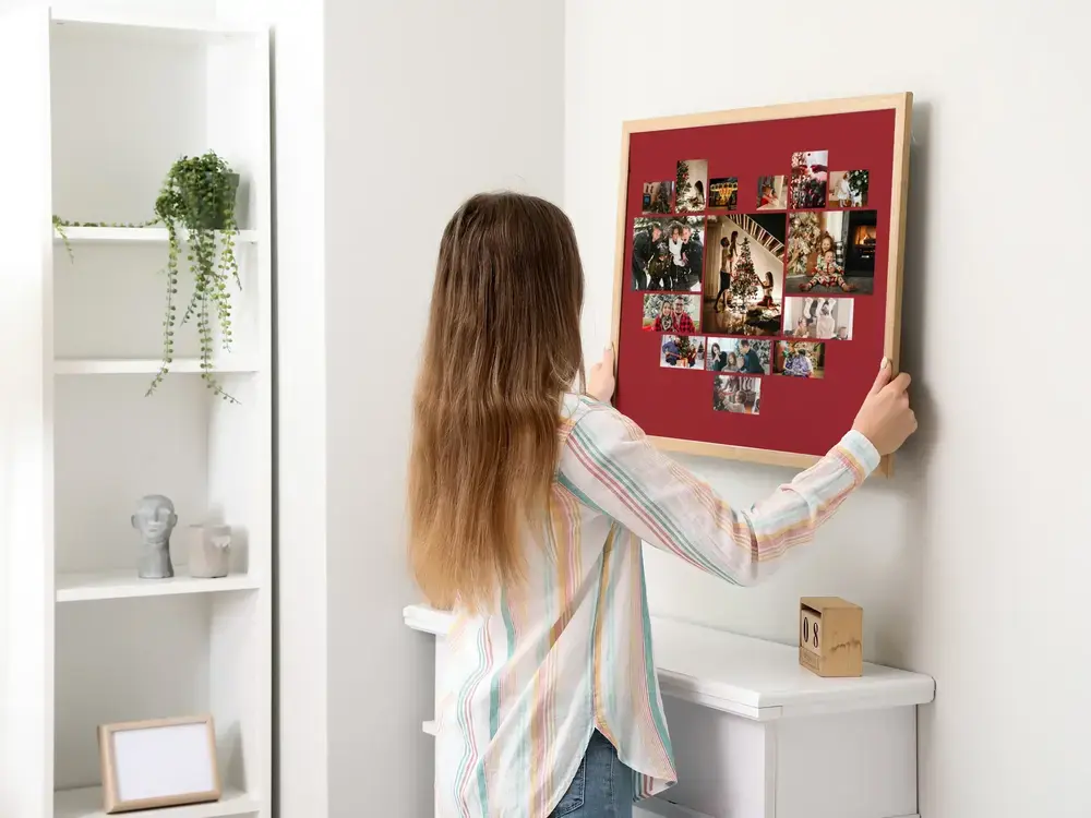 Fotocollage in Herzform auf Dunkelrot, im Holzrahmen an heller Wand, als Weihnachtsgeschenk für die Familie