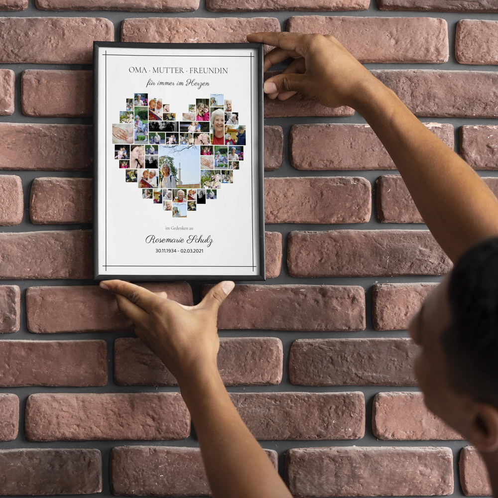 Personalisierte Trauercollage mit Fotos in Herzform im schwarzen Rahmen an einer Backsteinwand